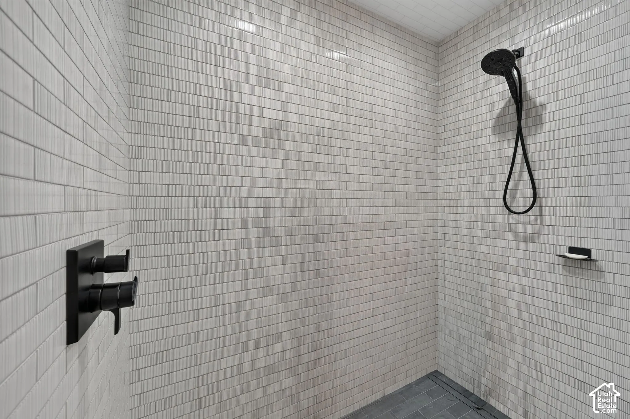 Walk-in shower with full wall tiling, matte black shower fixtures, and a tiled shower floor