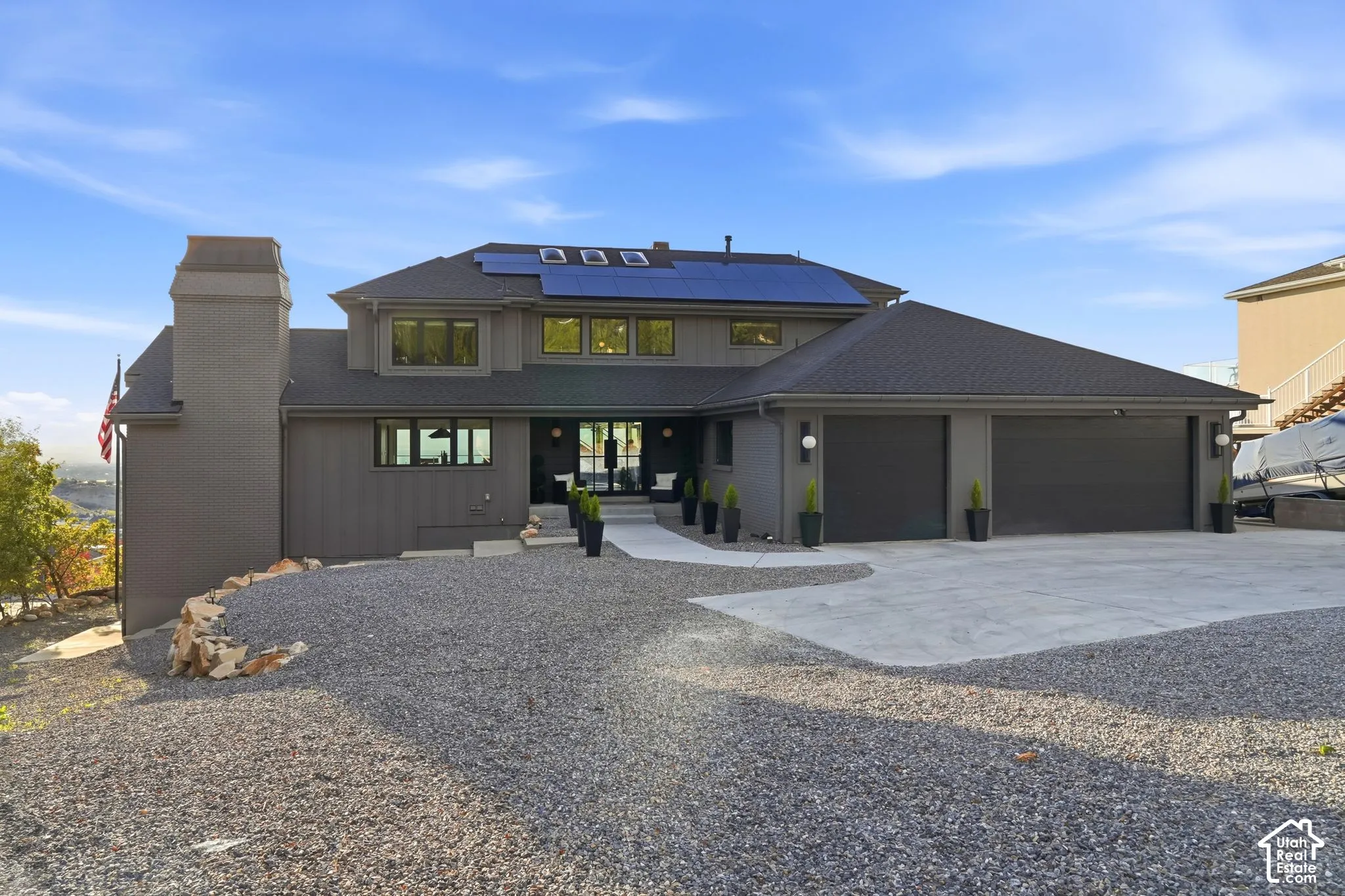 Contemporary exterior with a two-car garage, solar panels, and a gravel driveway