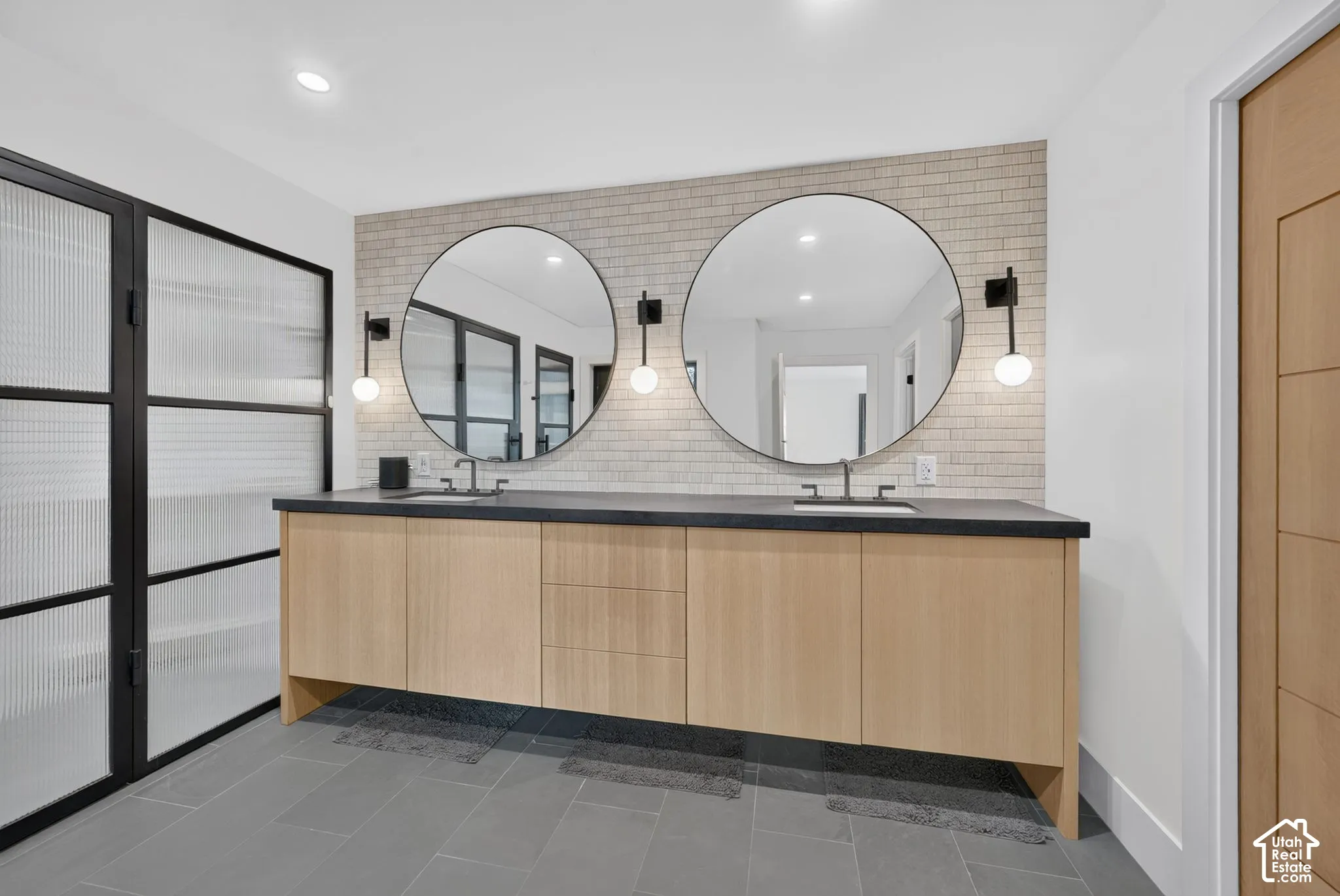 Dual vanity with wood-finish cabinetry and dark stone countertop