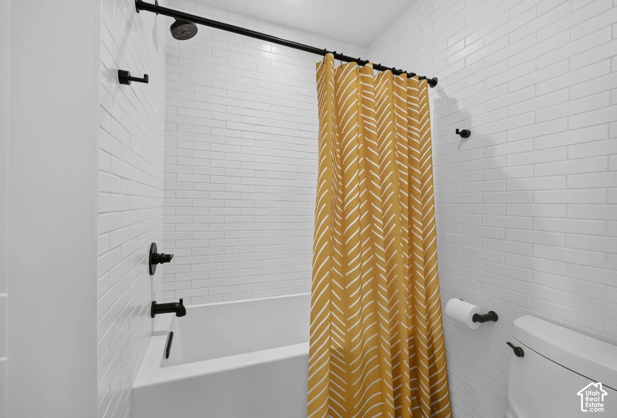 White subway tile surround, matte black shower fixtures, and a classic white bathtub