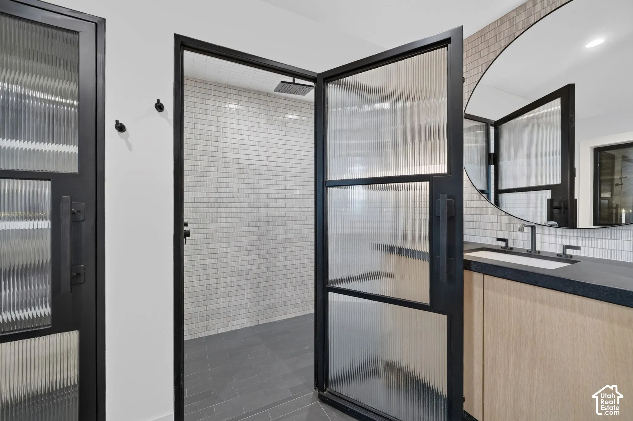 Shower with black-framed fluted glass doors, rainfall showerhead, and subway tile surround