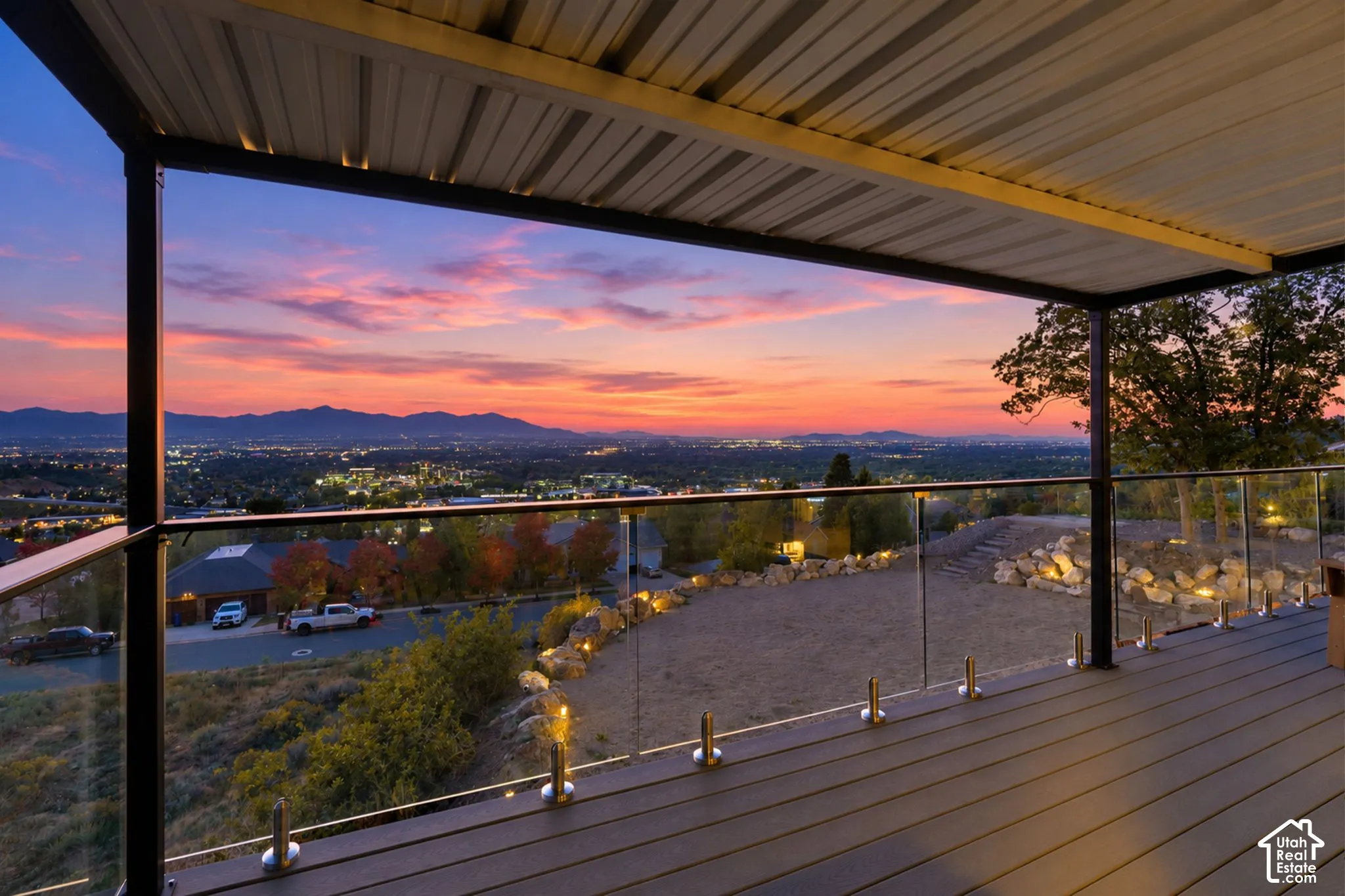 Covered outdoor deck with a corrugated metal ceiling, glass railing, and composite decking