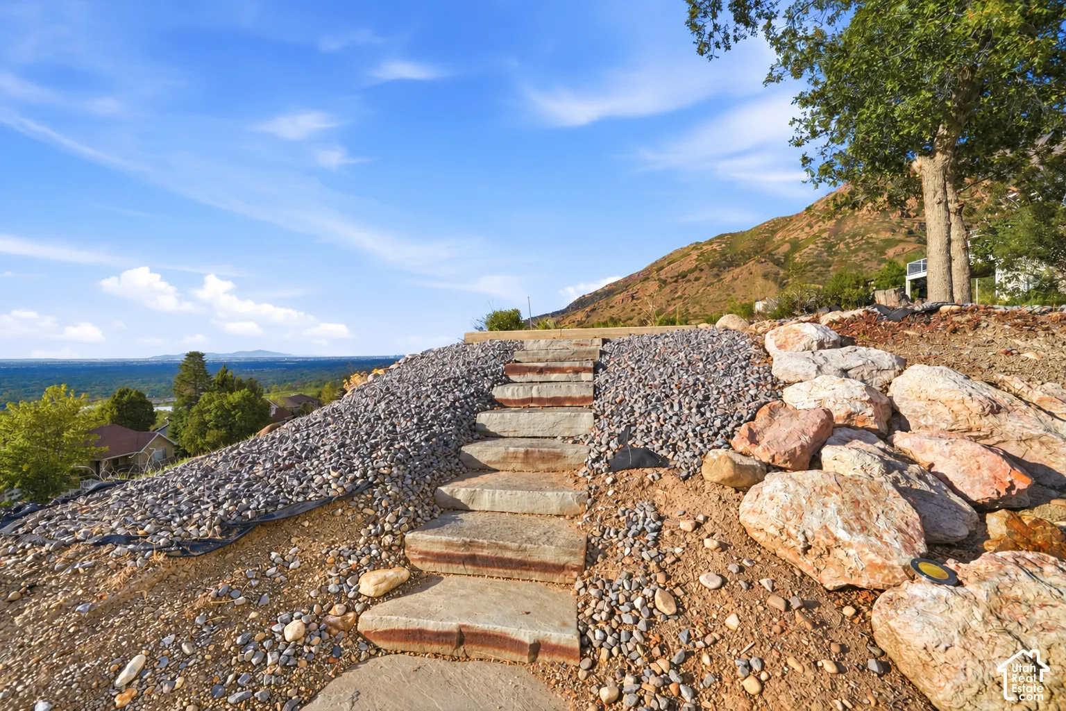 Terraced landscaping featuring stone steps, decorative gravel, and large natural boulders