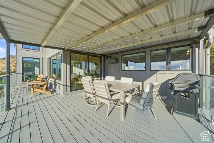 Expansive outdoor deck with a durable composite surface, glass panel railing, and a large corrugated metal roof overhang