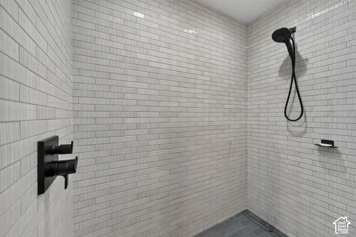 Walk-in shower with full wall tiling, matte black shower fixtures, and a tiled shower floor