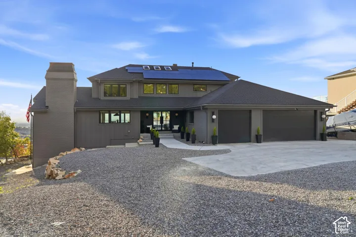 Contemporary exterior with a two-car garage, solar panels, and a gravel driveway