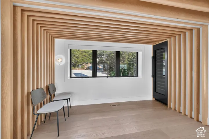 Wood-finish slat wall and ceiling treatment, wood-finish flooring, built-in sconce lighting, and a black-framed window