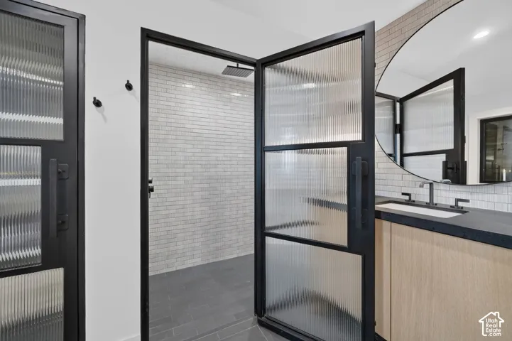 Shower with black-framed fluted glass doors, rainfall showerhead, and subway tile surround