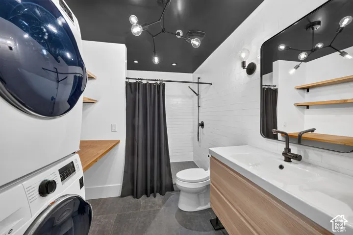 Bathroom featuring a dark ceiling, white subway tile shower surround, a wood-finish vanity with an integrated sink, and an exposed bulb chandelier