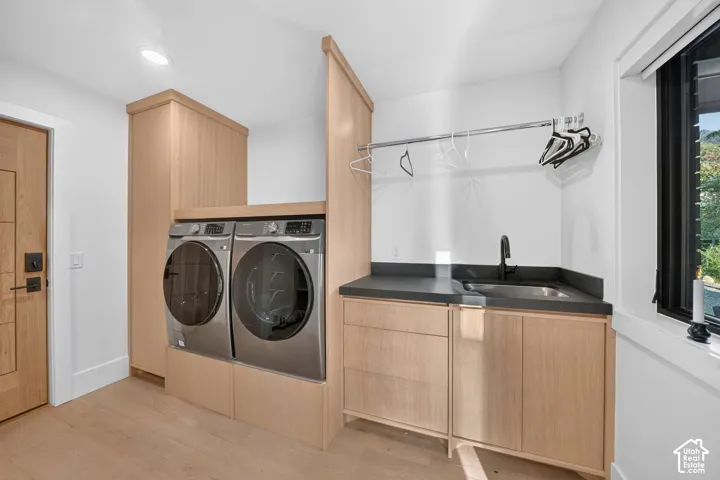 Dedicated laundry space featuring wood-finish cabinetry, a utility sink with a matte black faucet, and a hanging rod