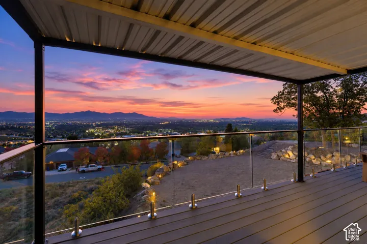 Covered outdoor deck with a corrugated metal ceiling, glass railing, and composite decking