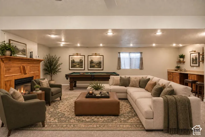 Wood-finish fireplace with hearth, recessed lighting, built-in wet bar with wood-finish cabinetry, and a pool table