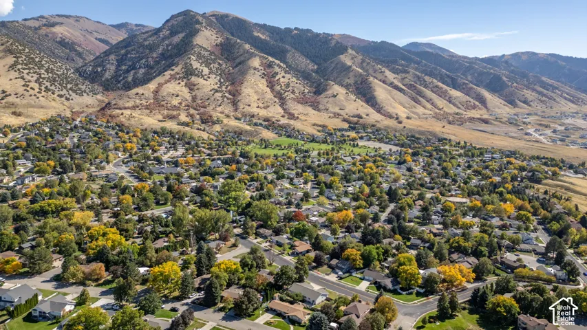 Expansive neighborhood setting with established homes and mature trees, framed by mountainous terrain