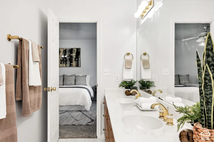 Dual vanity with white countertops, gold-finish fixtures, and a large mirror