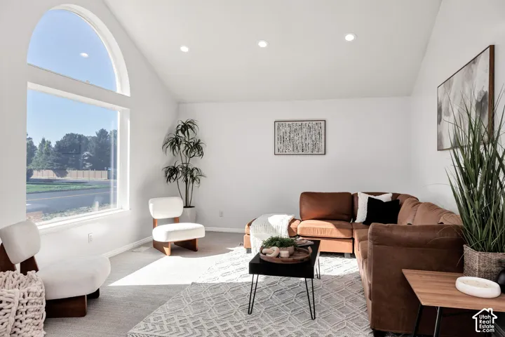 Vaulted ceilings with recessed lighting, large arched window, and carpeted flooring