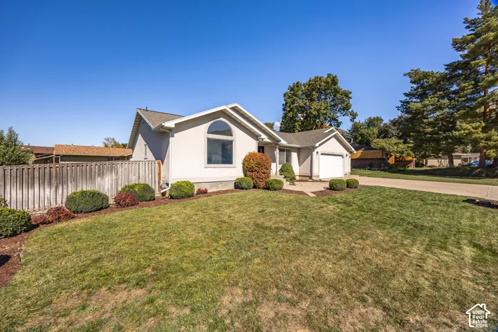 Single-story residence with a two-car garage, a rounded arched window, and a wood privacy fence