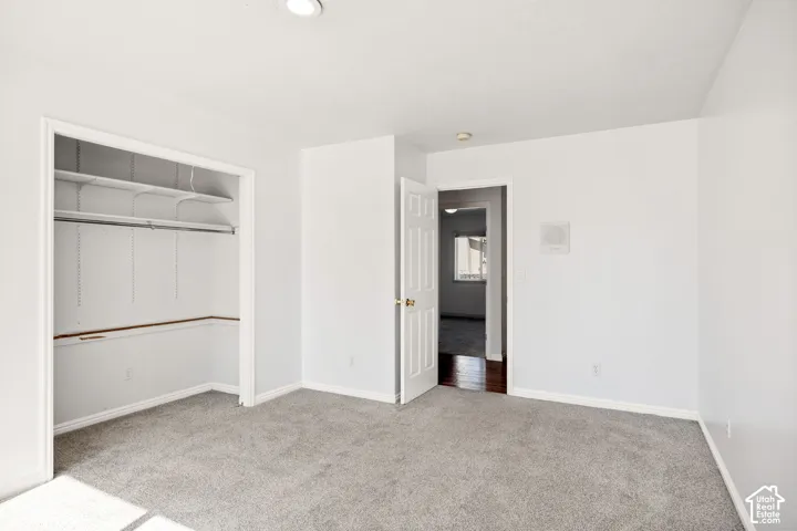 Recessed ceiling lighting, gray carpeting, white walls, and a built-in closet with shelving and hanging rods