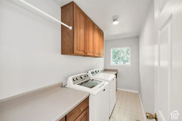 Laundry area featuring built-in wood cabinetry, light-toned countertops, a window, and tiled flooring