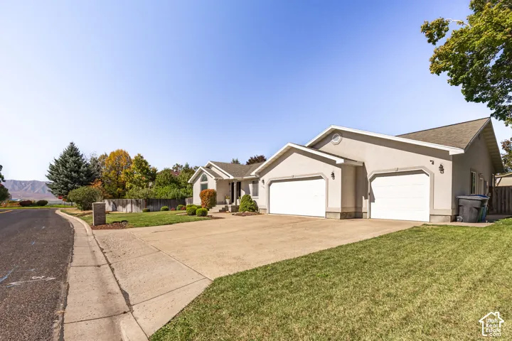 Stucco exterior with a pitched roof, attached two-car garage, concrete driveway, and established landscaping