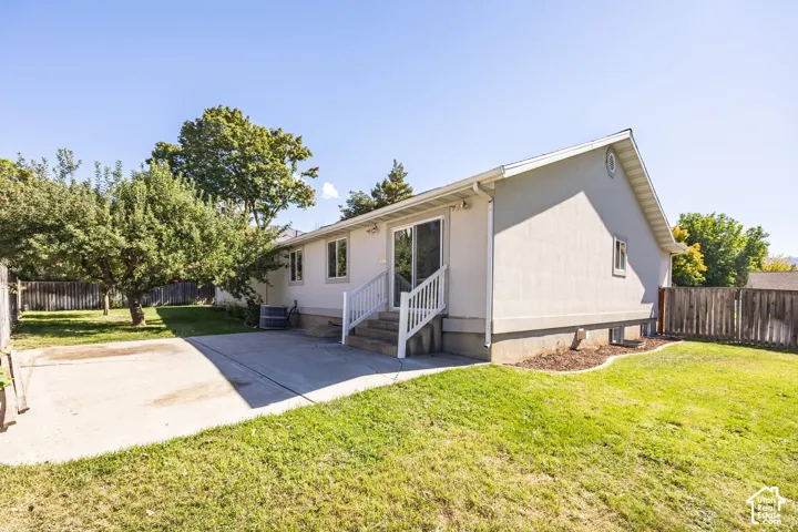 Exterior featuring a stucco finish, sliding glass door, patio, and a fenced yard with mature trees