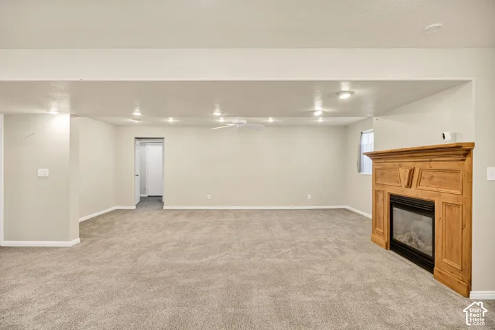 Recessed lighting and a ceiling fan illuminate the carpeted area