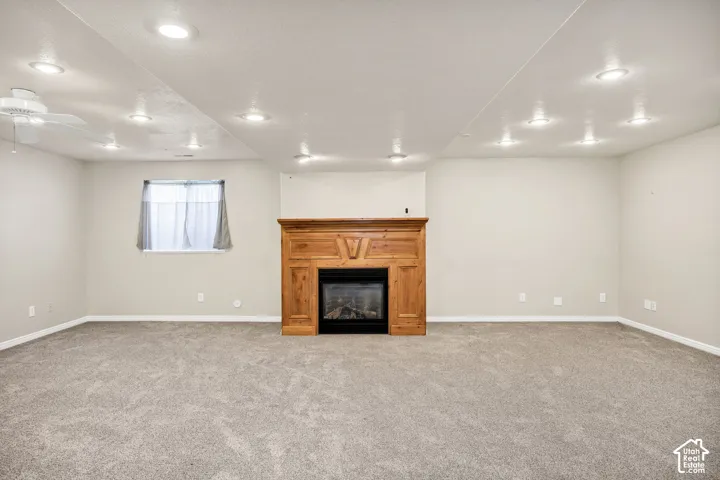 Spacious room with recessed lighting, plush carpeting, a ceiling fan, and a built-in fireplace with a wood mantel