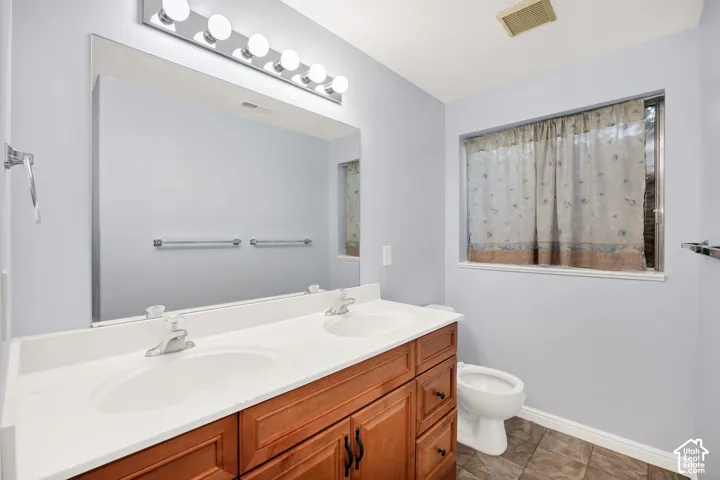 Dual vanity with individual sinks, wood-finish cabinetry, and a large wall-mounted mirror