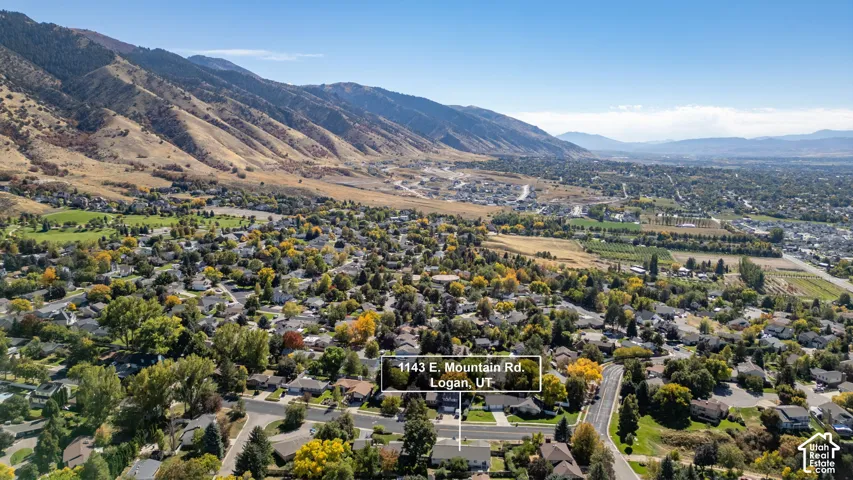 Expansive aerial perspective showcasing a residential neighborhood with surrounding mountains and a visible street grid