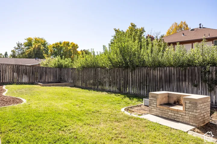 Expansive fenced yard featuring a grass lawn, wood privacy fencing, and a built-in outdoor brick cooking station