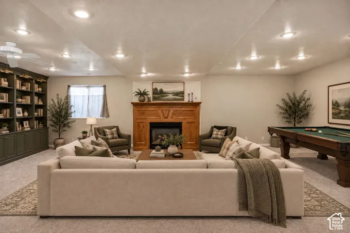 Built-in shelving with lower cabinetry, wood fireplace surround, recessed lighting, and ceiling fan