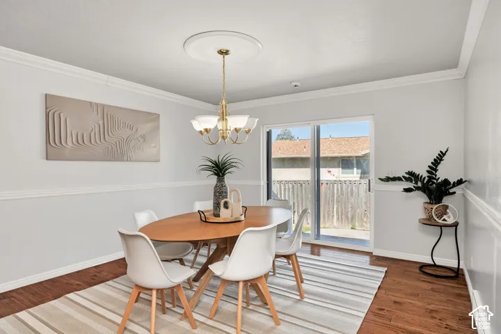 Wood-finish flooring, crown molding, and a chandelier with a ceiling medallion
