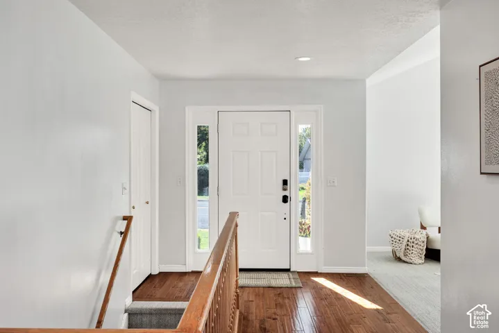 Entryway featuring wood-finish flooring, a white paneled door with sidelights, and recessed ceiling lighting
