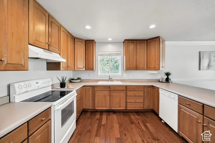 Wood-finish flooring, recessed lighting, wood cabinetry, built-in dishwasher, and a white oven range