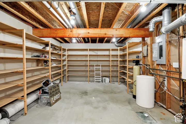 Extensive built-in shelving, exposed wood ceiling joists, concrete flooring, large support beam, and visible utility infrastructure