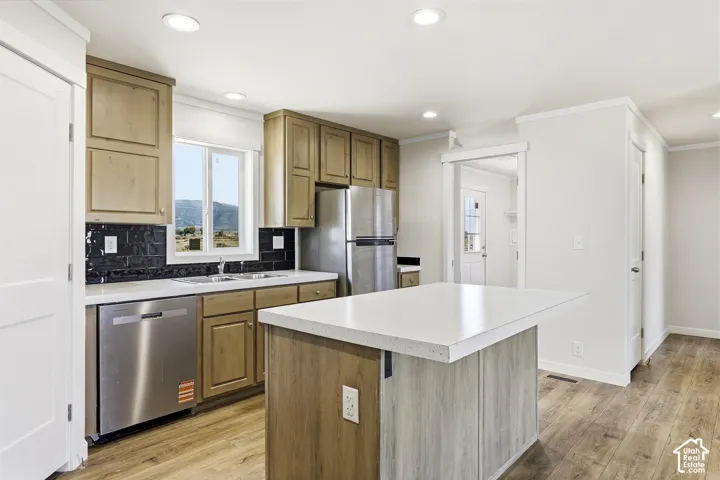 Kitchen featuring wood-finish cabinetry, stainless steel appliances, white countertops, a black subway tile backsplash, and wood-finish flooring