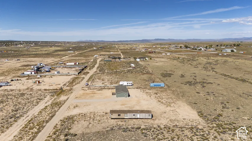 Expansive arid landscape featuring scattered residential structures and unpaved roads