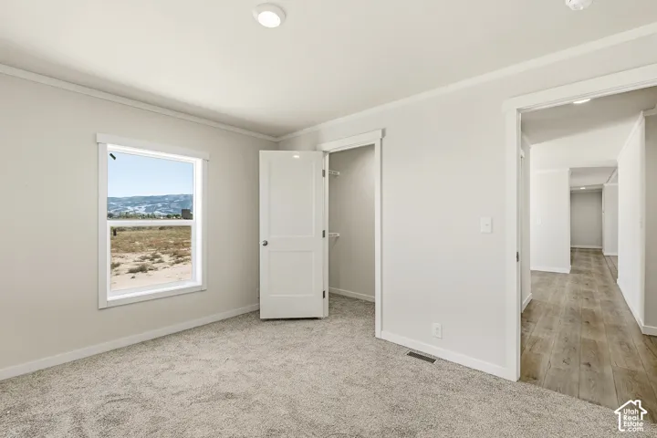 Light neutral wall paint, gray carpet flooring, white trim, recessed ceiling lighting, and a window with outdoor scenery