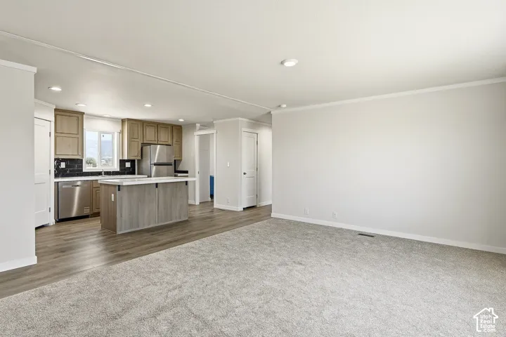 Open-concept living space featuring wood-finish flooring, recessed lighting, and crown molding