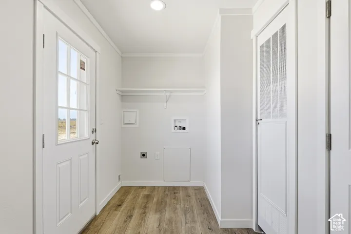 Utility space featuring wood-finish flooring, a white paneled door with window panes, and a white built-in shelf