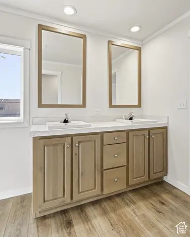 Dual vanity with light wood cabinetry, white countertops, and wood-finish flooring