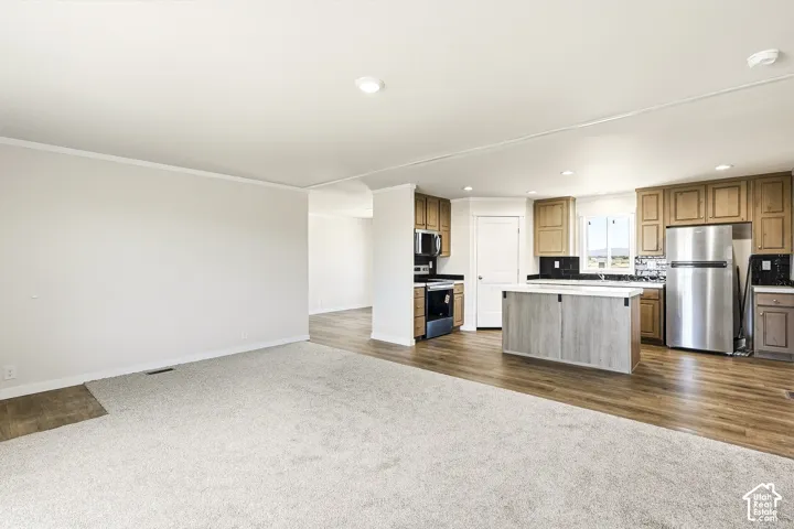 Open-concept living space featuring wood-finish flooring, a kitchen island with seating, stainless steel appliances, and wood cabinetry