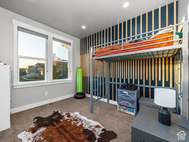 Recessed lighting illuminates the space, featuring a window with white trim and a unique accent wall with vertical wood paneling
