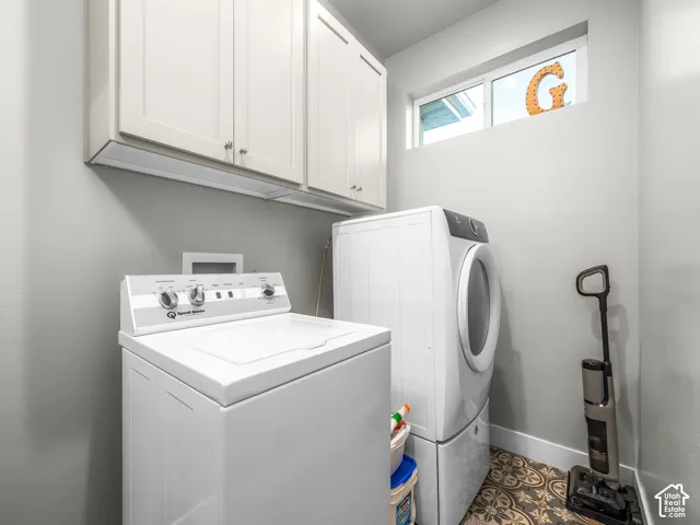 White upper cabinetry with brushed nickel hardware, light gray wall paint, patterned floor tile, and a transom window providing natural light
