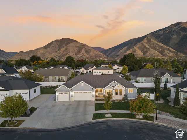 Mountain backdrop, a spacious driveway, a three-car garage, and established landscaping