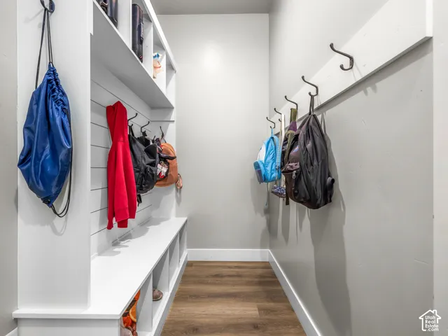 Built-in white storage bench with open cubbies, wood-finish flooring, and white shiplap-style wall paneling with hooks