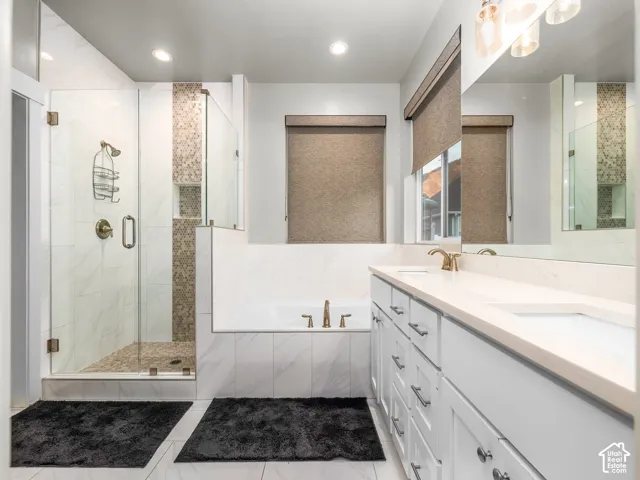 Walk-in shower with glass enclosure, built-in bathtub, double vanity with integrated sinks, and polished brass fixtures