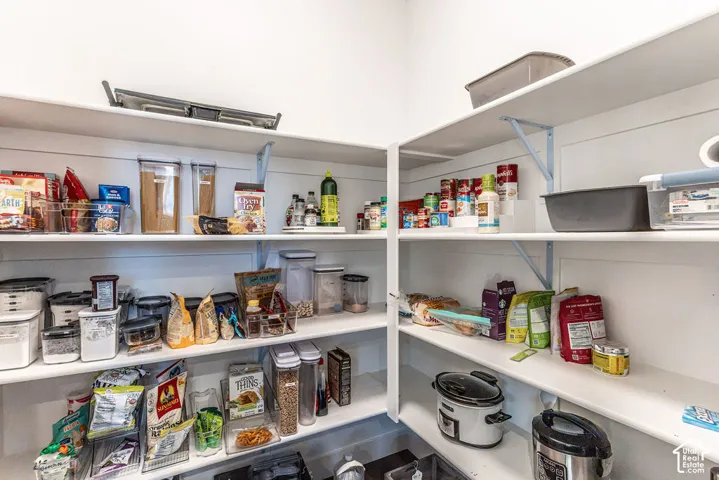 Corner pantry featuring white shelving and ample storage