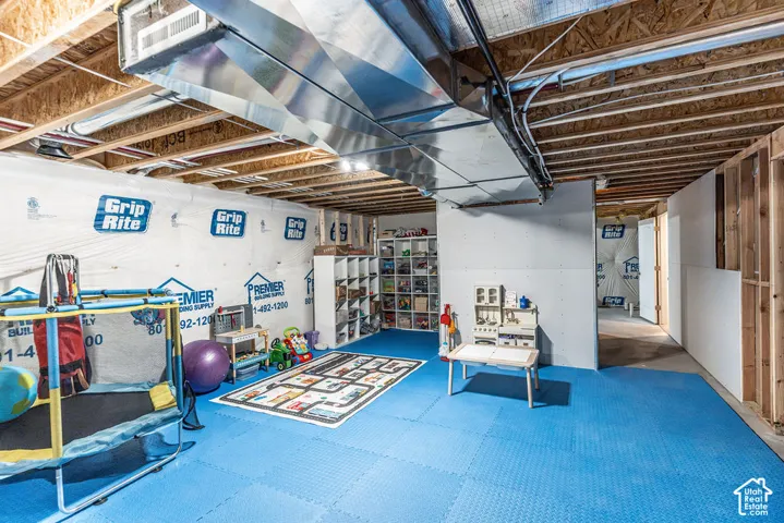 Unfinished lower level with exposed ceiling joists, open stud walls, and visible ductwork