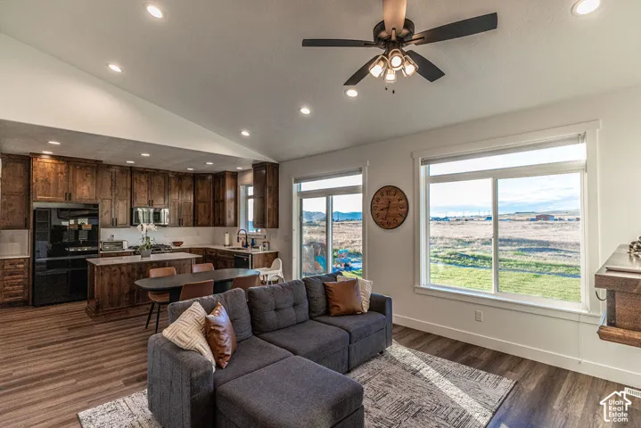 Spacious open-concept living area with vaulted ceilings, recessed lighting, wood-finish flooring, and expansive windows