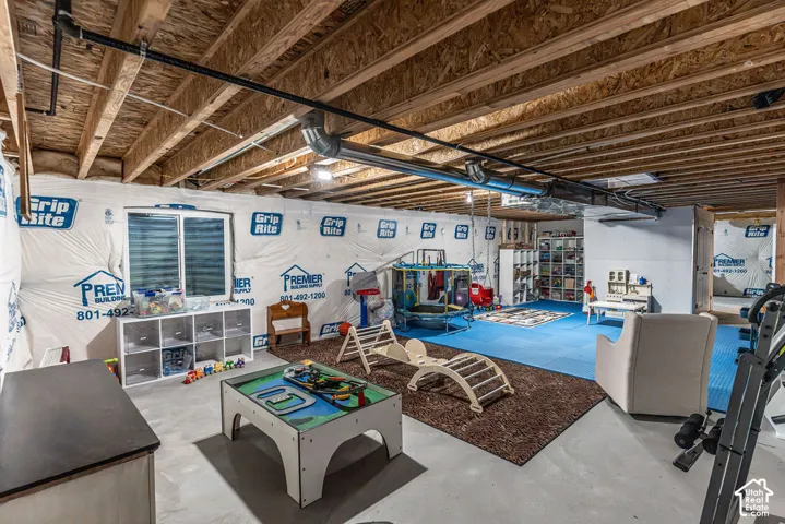 Unfinished basement space with exposed wood joists and concrete flooring, featuring a double window and visible insulation